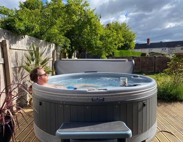 Customer in Orbis hot tub with cup of tea